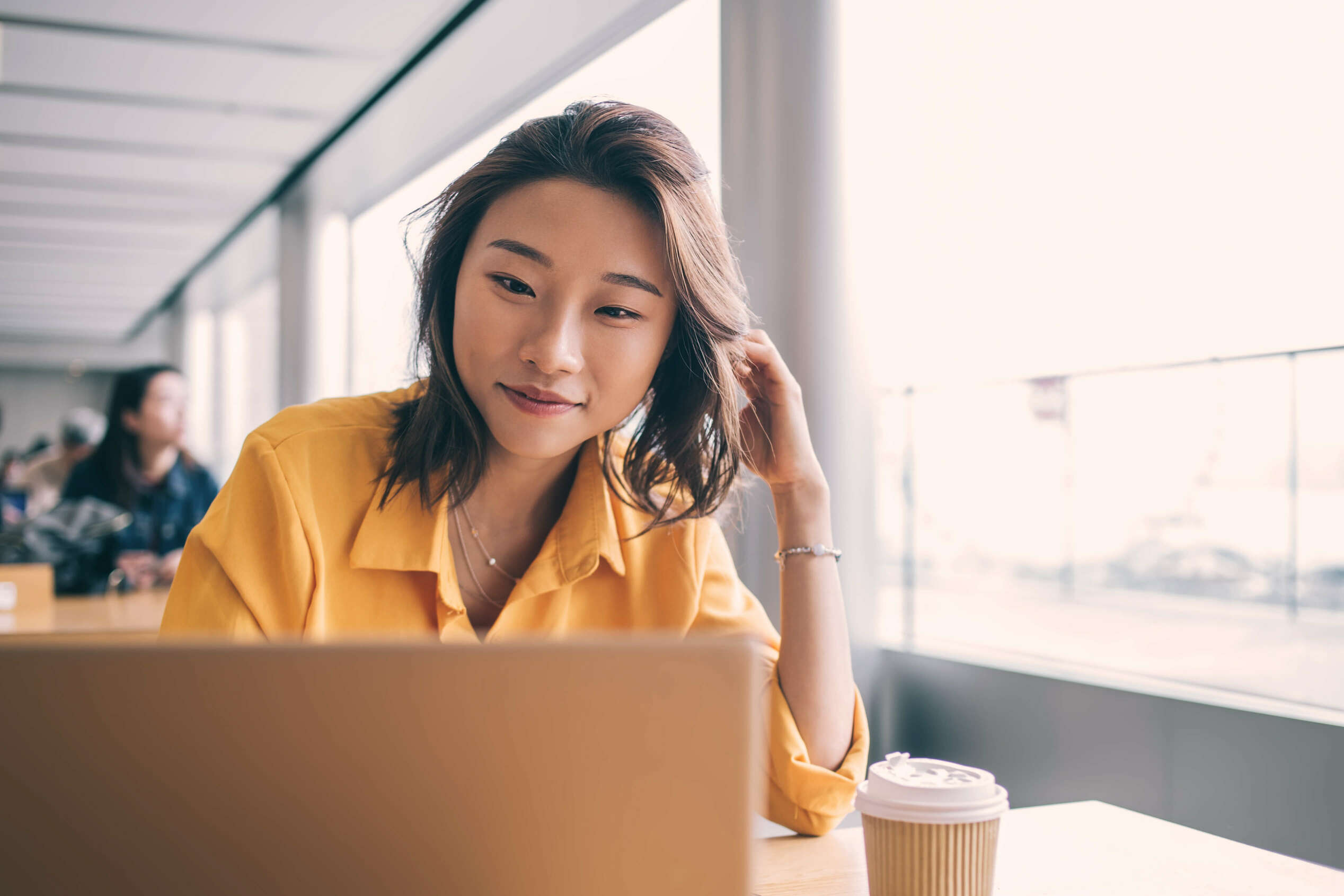 A woman working on a computer with a cup of coffee