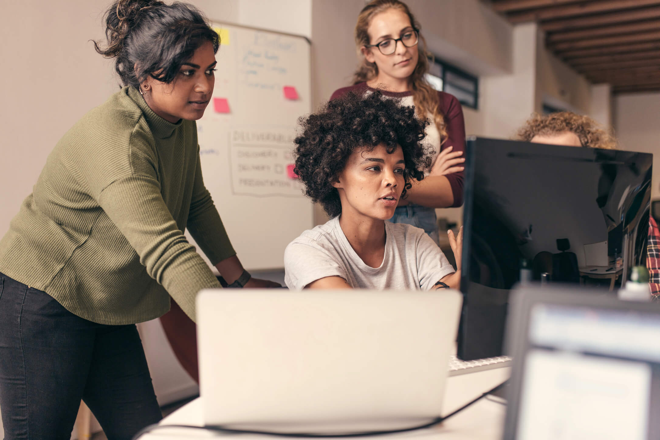 Four people collaborating around a computer