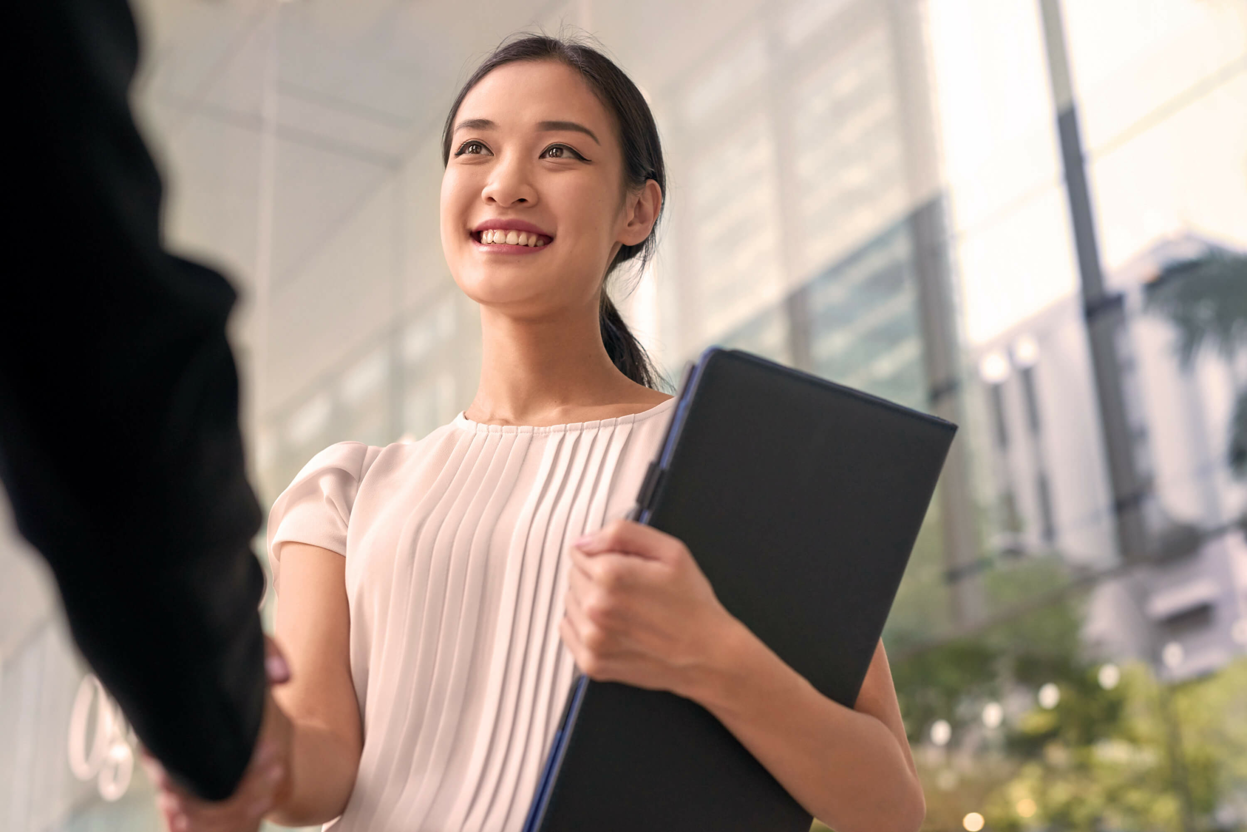 A woman shaking hands with someone out of frame